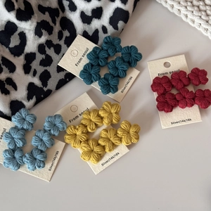 Detail of handcrafted crochet flower hair clips in four gradient colors on white cards