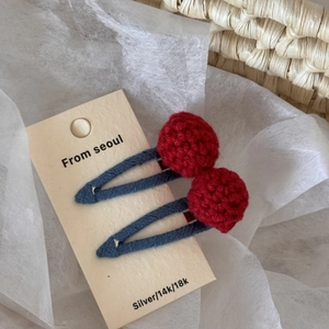 Detail of red handmade crochet ball hair clips with blue fabric wrapped metal clips