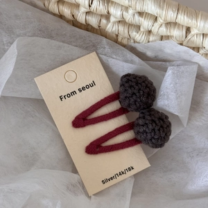 Close-up of handmade crochet ball hair clips in burgundy and brown on card