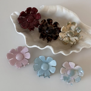 Détail de pinces à cheveux fleurs en acétate en six coloris sur une assiette coquillage