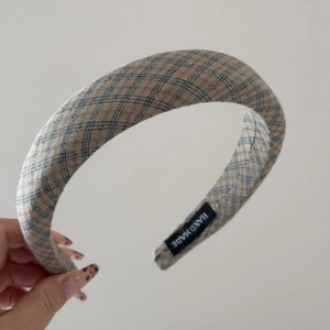 Close-up of handmade wide padded headband with gray and brown retro plaid fabric texture