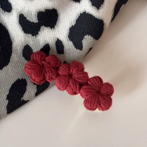 Detail of three handmade red crochet flowers on a stylish knit hairpin with soft yarn texture