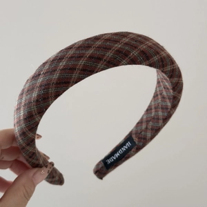 Detail of handmade padded headband with red and black plaid fabric and quality woven label