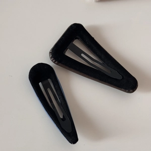 Détail de pinces à cheveux triangulaires en cuir marron et bleu marine avec clip