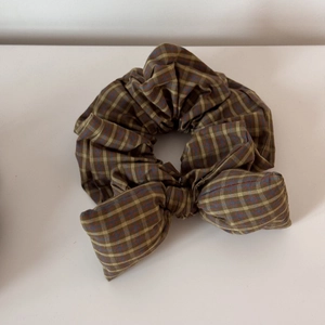 Detailed view of vintage plaid bow scrunchie in earthy tones on a white surface