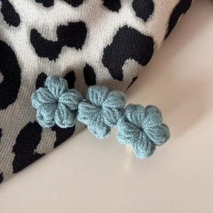 Detailed view of three light blue hand-knitted crochet flowers for hair clips