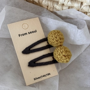 Detail of yellow crochet yarn ball hair clips on a card board for girls accessories