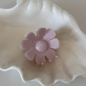 Vue détaillée d'une pince à cheveux fleur rose clair à paillettes sur un plateau