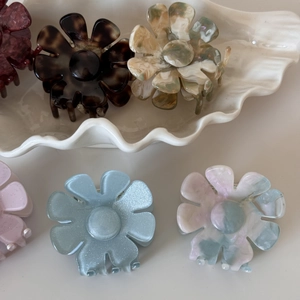 Pinces à cheveux en acétate en forme de fleur colorées sur un plateau en coquillage