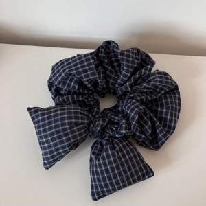Detail of navy blue plaid hair scrunchie with a large bow showing fabric texture