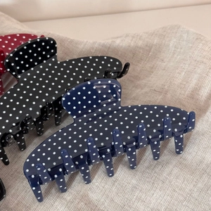 Macro shot of polka dot hair claws in blue and black acetate with secure grip design