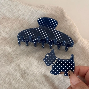 Close-up of polka dot acetate hair claw clip and cute dog hair pin on linen fabric