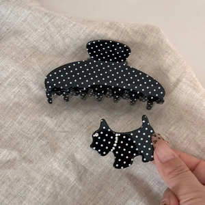 Close-up of black and white polka dot acetate hair claw and terrier-shaped clip with rhinestones