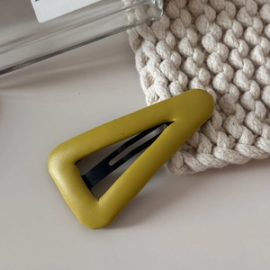 Gros plan détaillé d'une pince à cheveux triangulaire jaune vif en cuir texturé