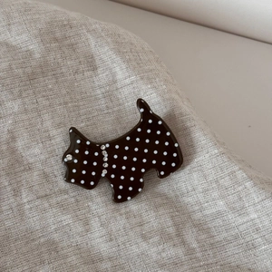 Macro shot of dark brown polka dot dog hair clip with sparkling rhinestone details