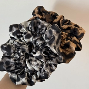 Detailed macro view of handmade leopard print hair scrunchies with soft silk satin texture