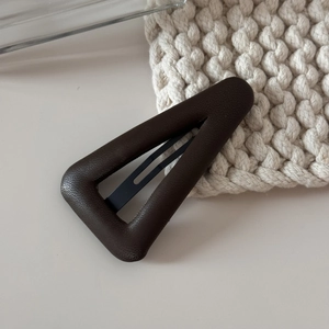 Vue macro d'une pince à cheveux triangulaire en cuir marron avec texture grainée