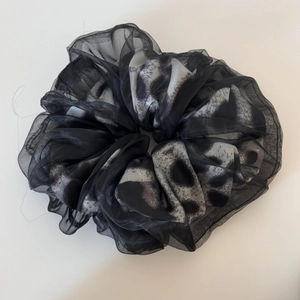 Close-up of leopard print chiffon hair scrunchie with soft pleated texture and semi-sheer fabric
