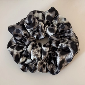 Close-up of leopard print satin scrunchie with detailed stitching and handmade label
