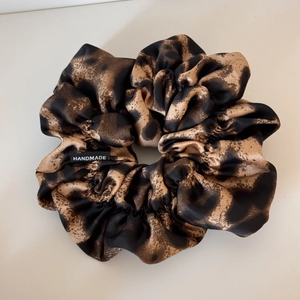 Close-up of leopard print satin scrunchie with handmade woven label detail
