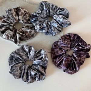 Gros plan de quatre chouchous en velours à motif léopard aux tons gris et violets élégants