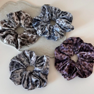 Gros plan de quatre chouchous en velours à imprimé léopard en marron, bleu, violet et gris