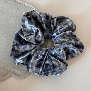 Détail d'un chouchou en velours à motif léopard avec texture douce et étiquette