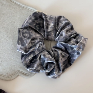 Gros plan sur un chouchou en velours léopard montrant la texture et l'étiquette de marque