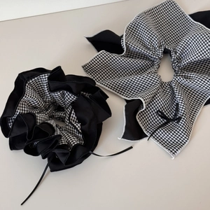 Detail view of black and white plaid scrunchies with elegant bow ribbon and wavy edges