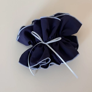 Close-up of navy blue plaid fabric scrunchie with light blue edges and grey ribbon detail