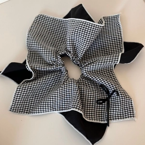 Detail of large gingham and black fabric scrunchie with a small delicate bow