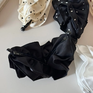 Nahaufnahme von Satin-Bananenclips mit Polka-Dots und Rüschendetails in Lagenoptik