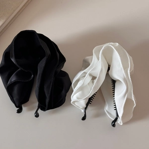 Nahaufnahme von schwarzen und weißen Satin-Bananenspangen mit Rüschenstoff und Kunststoffzähnen