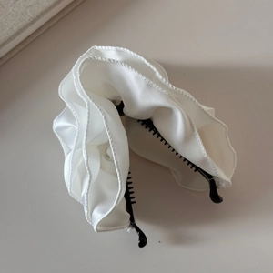 Nahaufnahme der eleganten weißen Satin-Haarklammer mit gerüschtem Stoff und feiner Naht