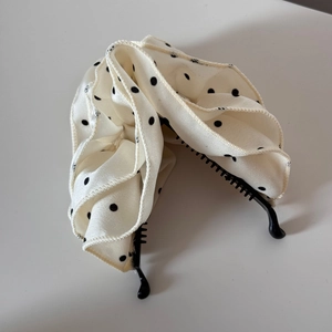 Detailansicht der beigen gepunkteten Faltenstoff-Struktur auf der Bananen-Haarspange