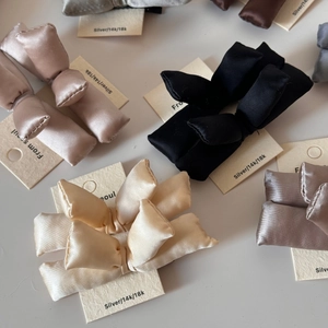 Close-up of assorted padded satin bow hair clips in multiple colors on branded cards