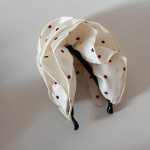 Detailansicht der beigen Satin-Bananenspange mit roten Punkten und mehrlagiger Stoffstruktur