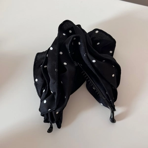Detailansicht einer schwarzen Bananenspange mit mehrlagiger gepunkteter Satinschleife