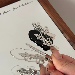 Detailansicht der Metallblumen-Haarklammern auf einer Spiegelfläche mit Reflexion