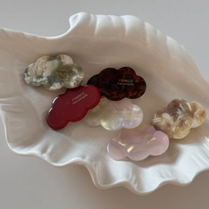 Detailed macro view of acetate mini cloud hair clips in multiple colors with gold logo
