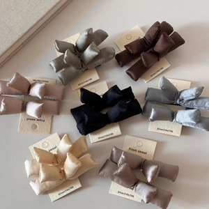Flat lay of colorful padded satin bow hair clips in grey, coffee, nude and morandi blue