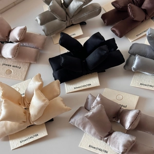 Close-up of padded satin bow hair clips in multiple colors with elegant silk texture