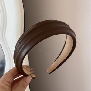 Detailed macro view of dark brown faux leather headband with premium lychee texture