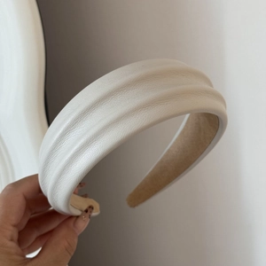 Detailed macro of cream faux leather headband showing litchi texture and padded design