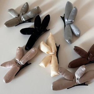 Detailed close-up showing multiple colors of padded satin bow hair clips on white background
