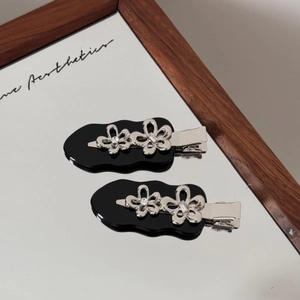 Detailansicht silberner Blumen-Haarspangen mit schwarzer Acrylbasis auf Spiegelglas