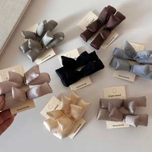 Flat lay of multiple 3D padded satin bow hair clips in various Morandi colors on cards