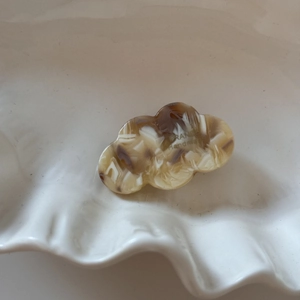 Close-up of cloud-shaped acetate hair clip with brown marble pattern in white tray