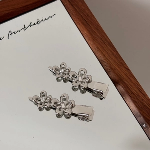 Makroaufnahme von silbernen Blumen-Haarklammern mit Strass auf einer Spiegelfläche