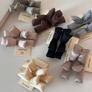 Detailed view of plush 3D padded bow hair clips in neutral satin fabric colors